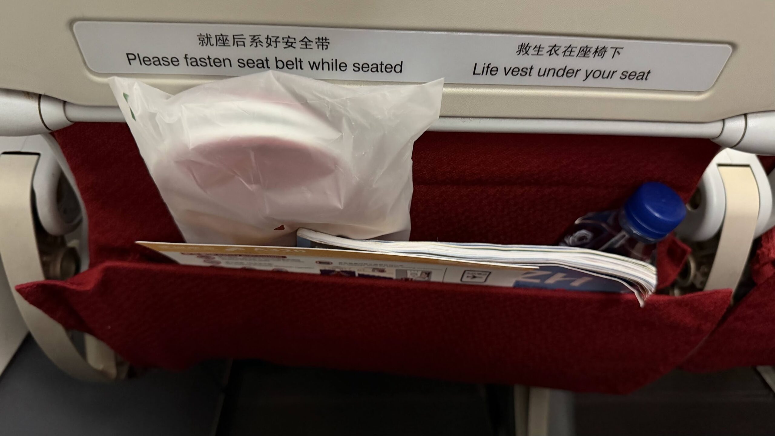 Shenzhen Airlines premium economy seat pocket with slippers and bottled water